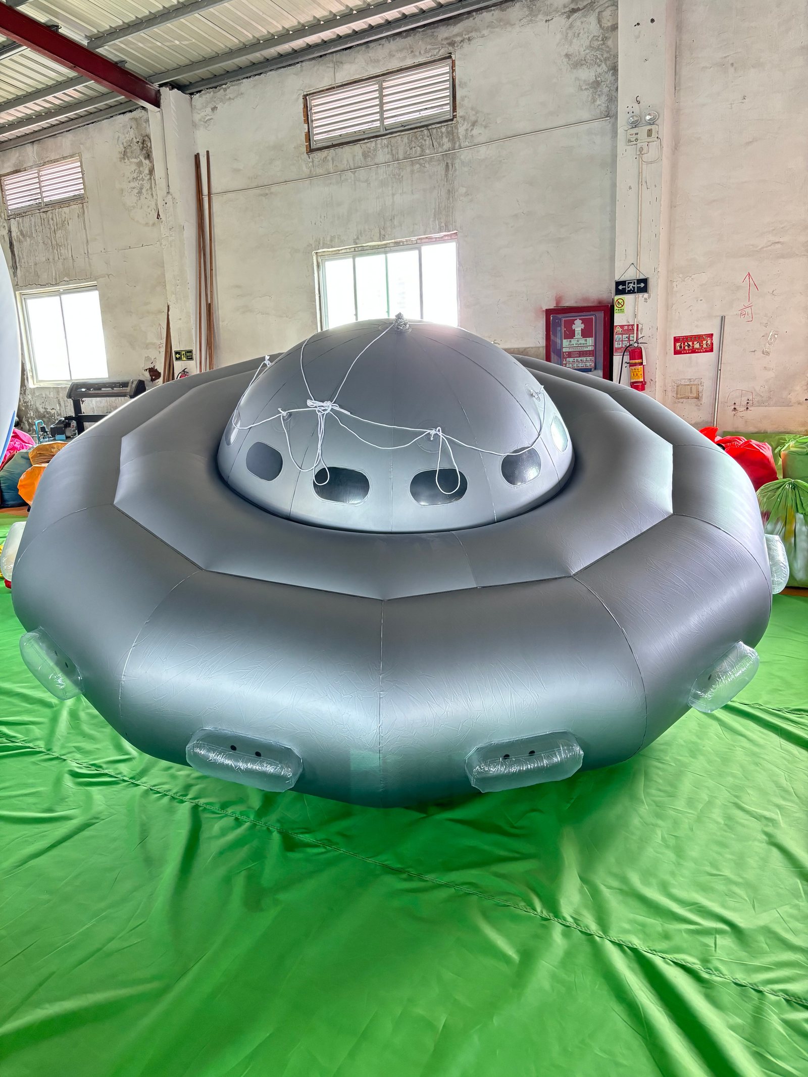 Large silver flying-saucer-shaped inflatable fully inflated on a factory floor for testing.