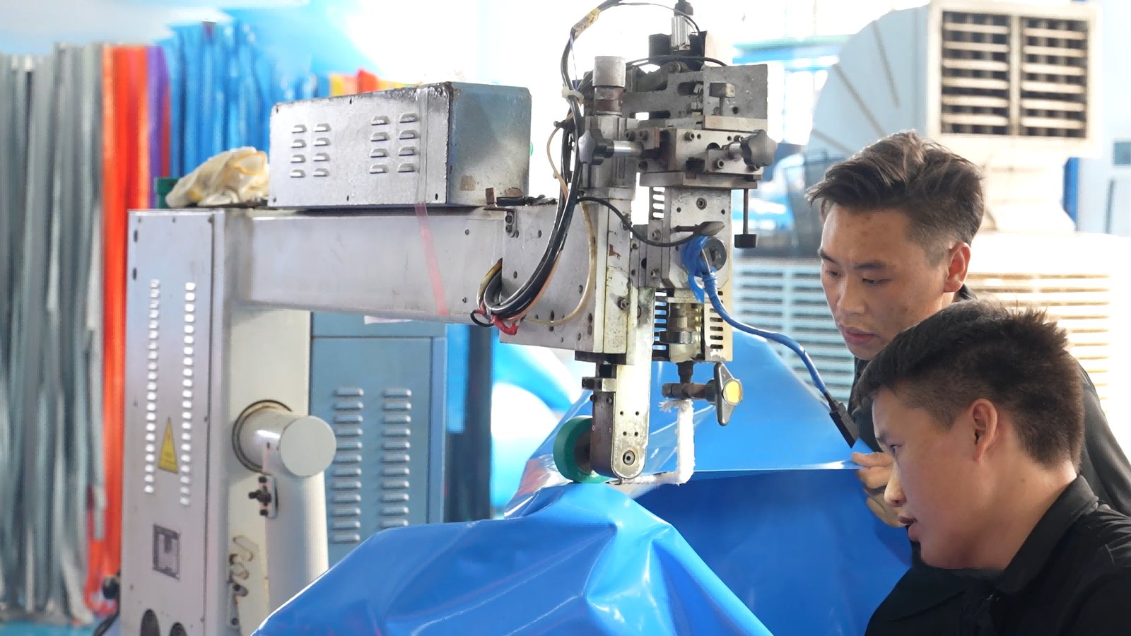 Manufacturing partner technicians heat-welding blue inflatable material.