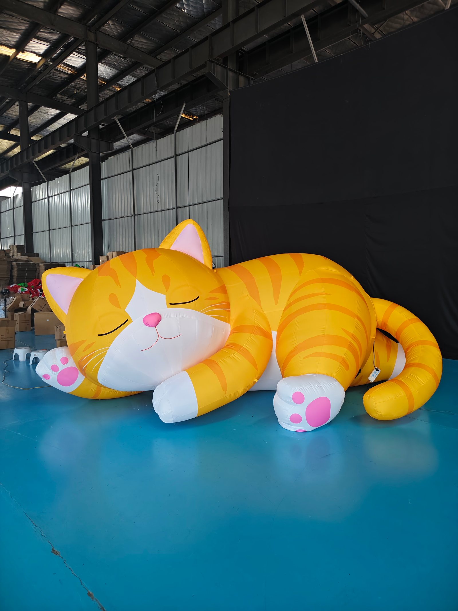 Oversized orange sleeping cat inflatable during a factory inflation test.